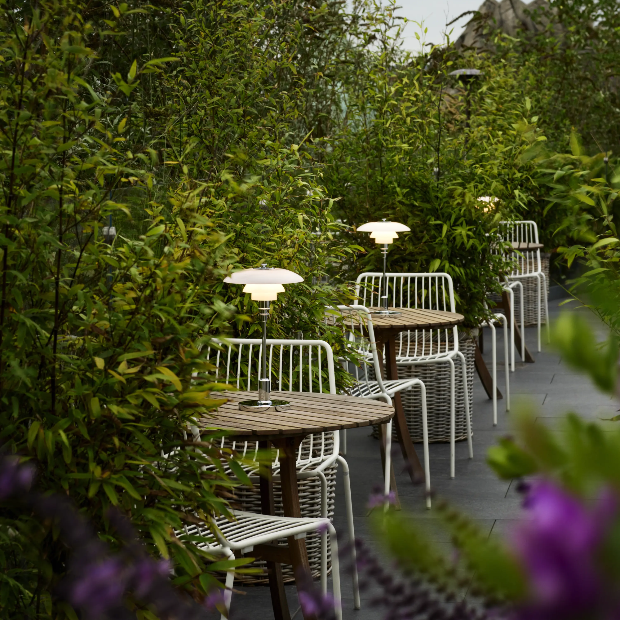 The chrome PH 2/1 Portable Lamp from Louis Poulsen in an outdoor cafe on top of cafe tables.