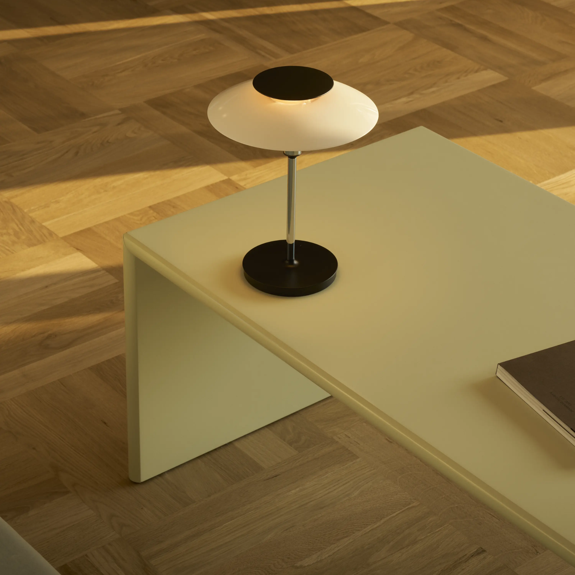 The opal white and high luster chrome plate PH 80 Portable Lamp from Louis Poulsen in a family area on top of a table.