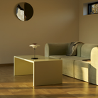 The opal white and high luster chrome plate PH 80 Portable Lamp from Louis Poulsen in a living space on top of a coffee table in front of a couch.