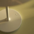 The opal white and white plate PH 80 Portable Lamp from Louis Poulsen in a living room on a table, shown close up.
