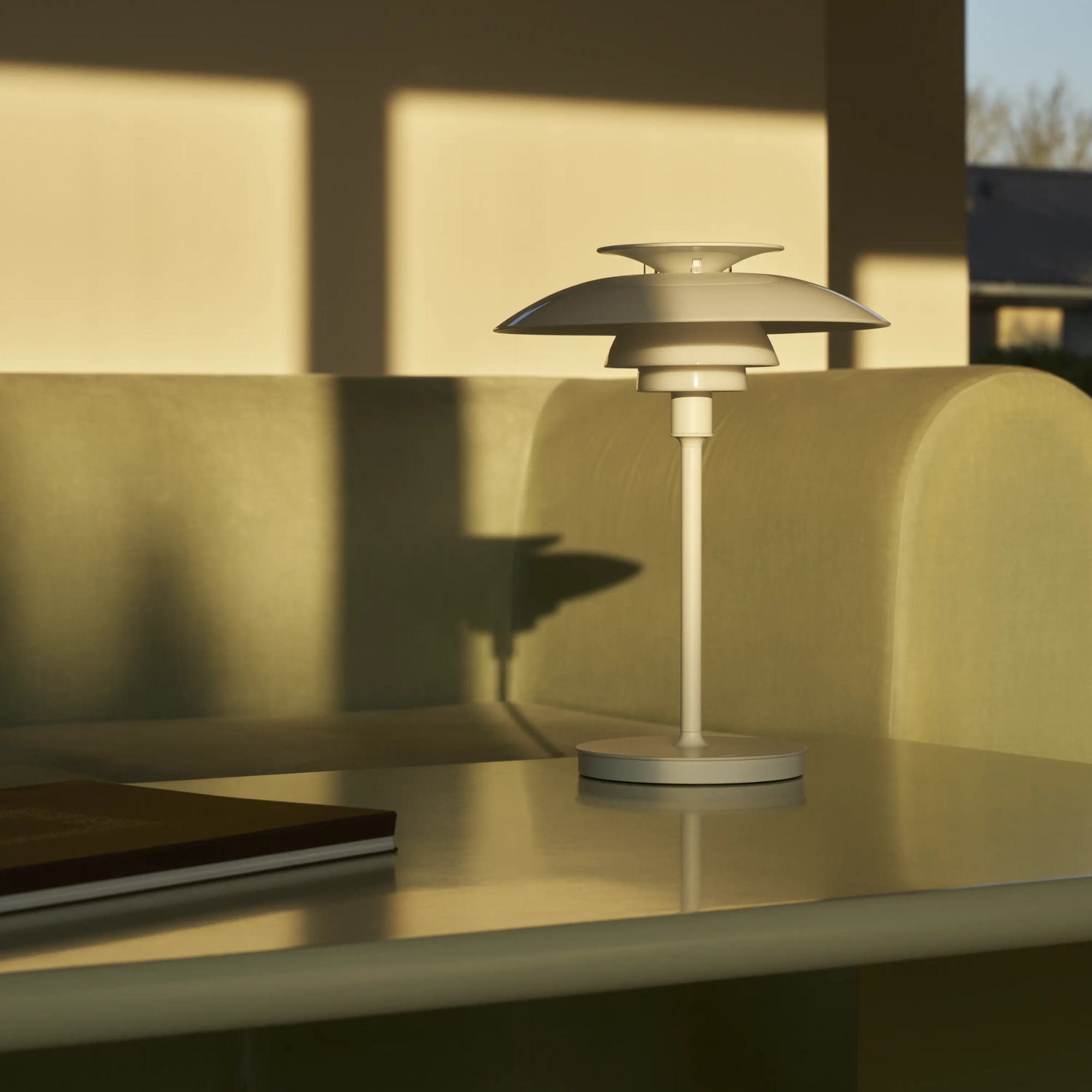 The opal white and white plate PH 80 Portable Lamp from Louis Poulsen on top of a table in a living space.