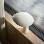 The cloud white Rumee 220 Portable Lamp from Louis Poulsen in a guest room.