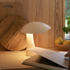 The cloud white Rumee 220 Portable Lamp from Louis Poulsen in a home library.