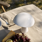 The cloud white Rumee 220 Portable Lamp from Louis Poulsen on a patio.