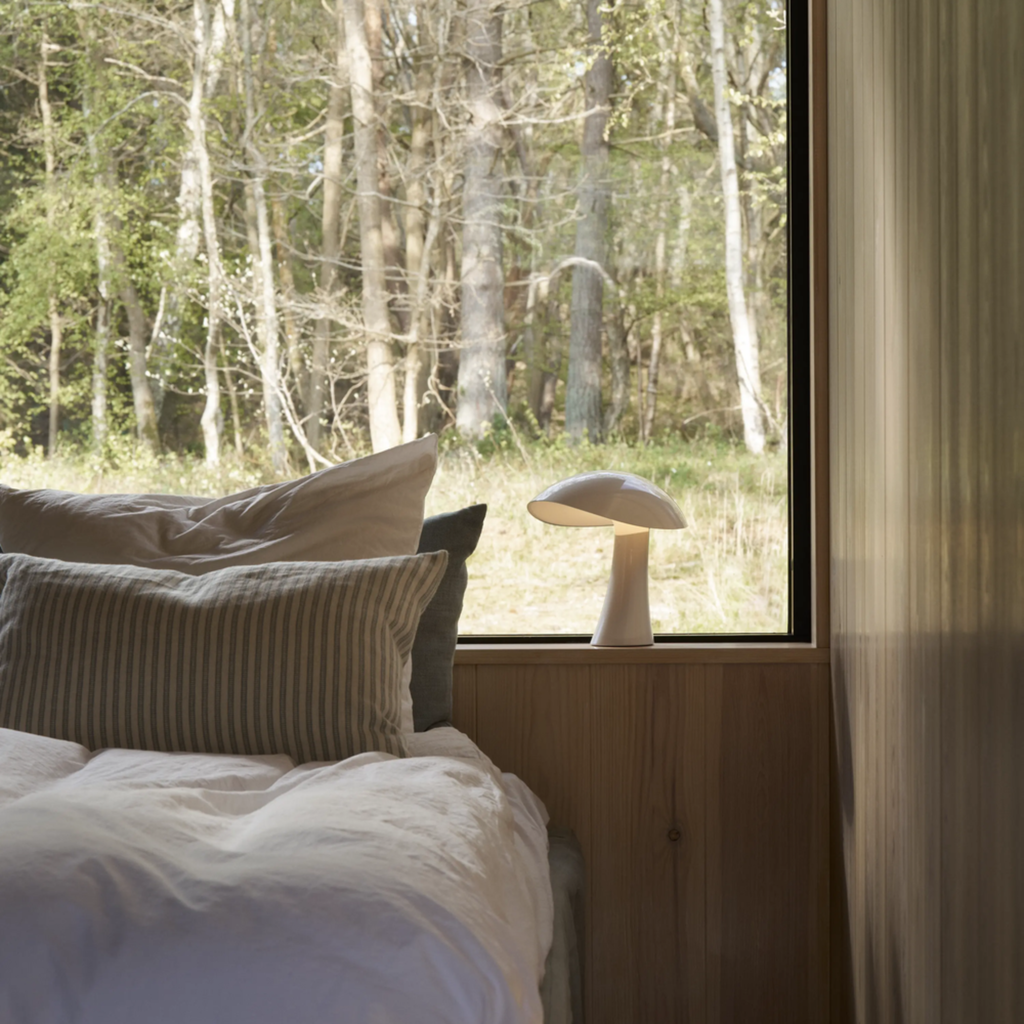 The cloud white Rumee 220 Portable Lamp from Louis Poulsen in a primary bedroom.