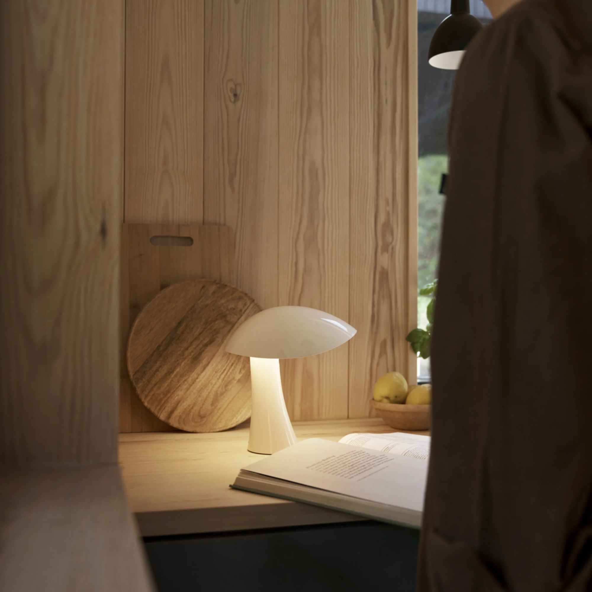 The cloud white Rumee 220 Portable Lamp from Louis Poulsen in a reading space.
