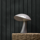 The earth gray Rumee 220 Portable Lamp from Louis Poulsen in a lounge.