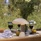 The earth gray Rumee 220 Portable Lamp from Louis Poulsen in an outdoor dining setting.