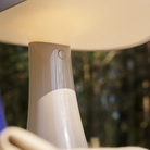 The earth gray Rumee 220 Portable Lamp from Louis Poulsen in an outdoor living space.