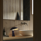 The night blue Rumee 220 Portable Lamp from Louis Poulsen in a bathroom.