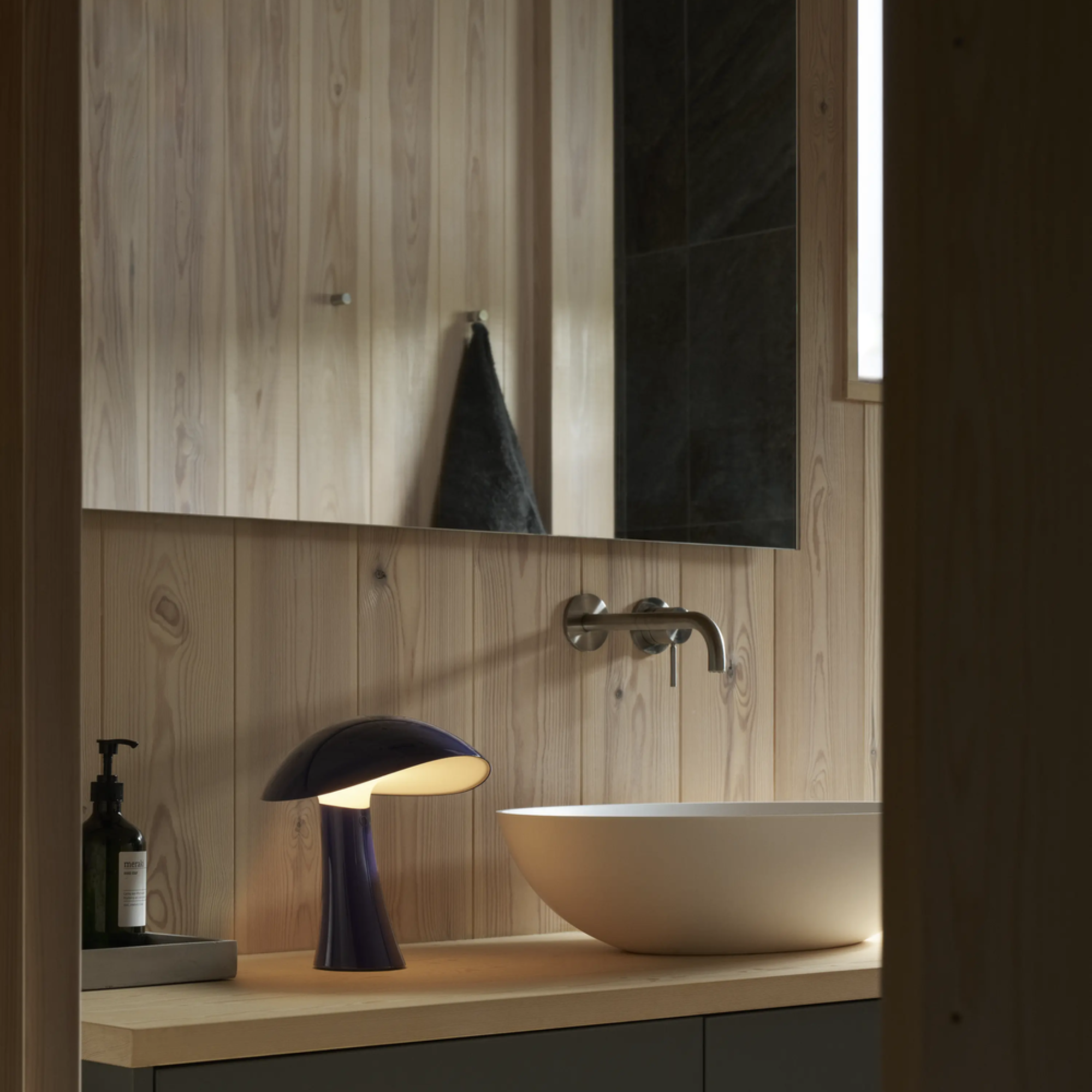 The night blue Rumee 220 Portable Lamp from Louis Poulsen in a bathroom.