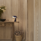 The night blue Rumee 220 Portable Lamp from Louis Poulsen in a hallway.