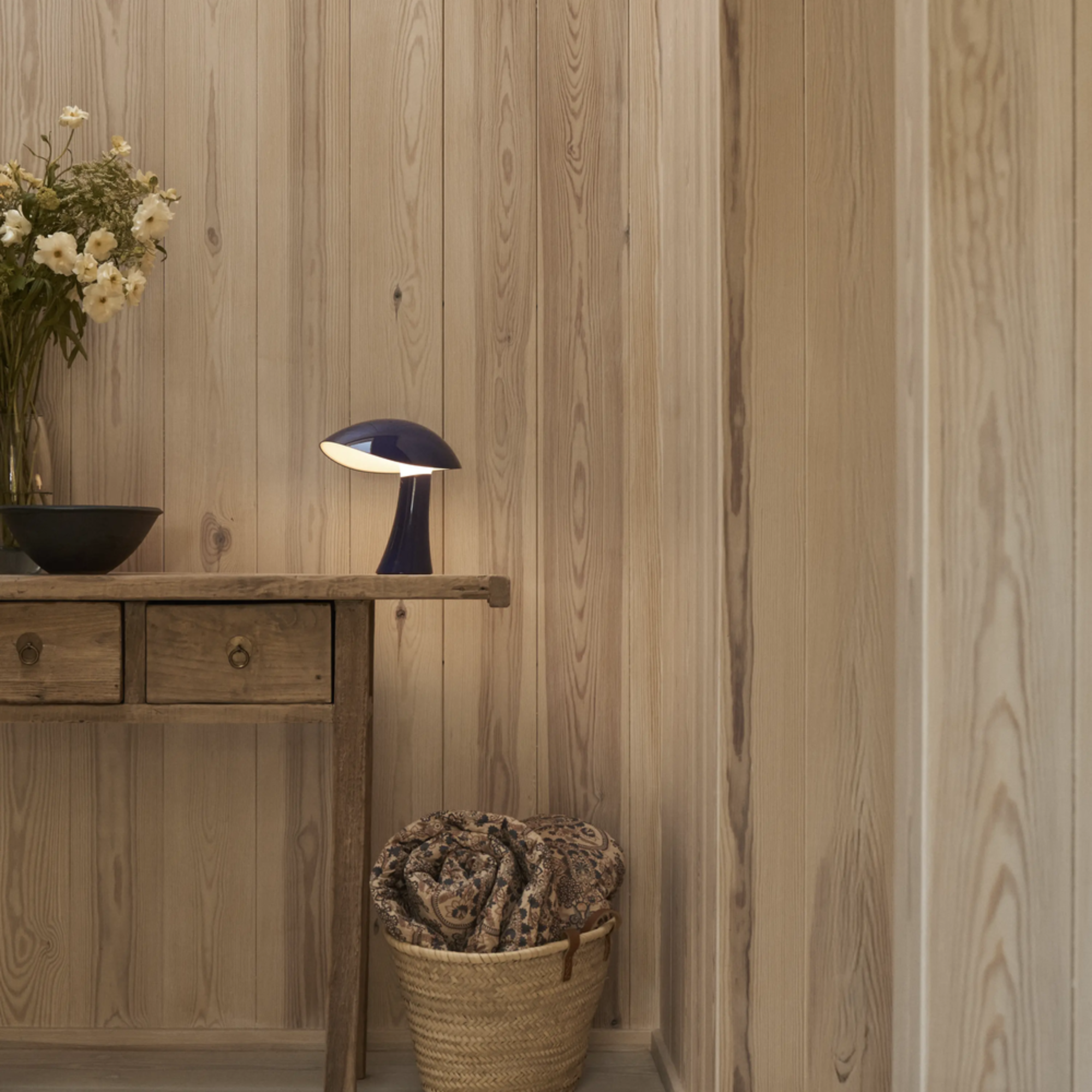 The night blue Rumee 220 Portable Lamp from Louis Poulsen in a hallway.
