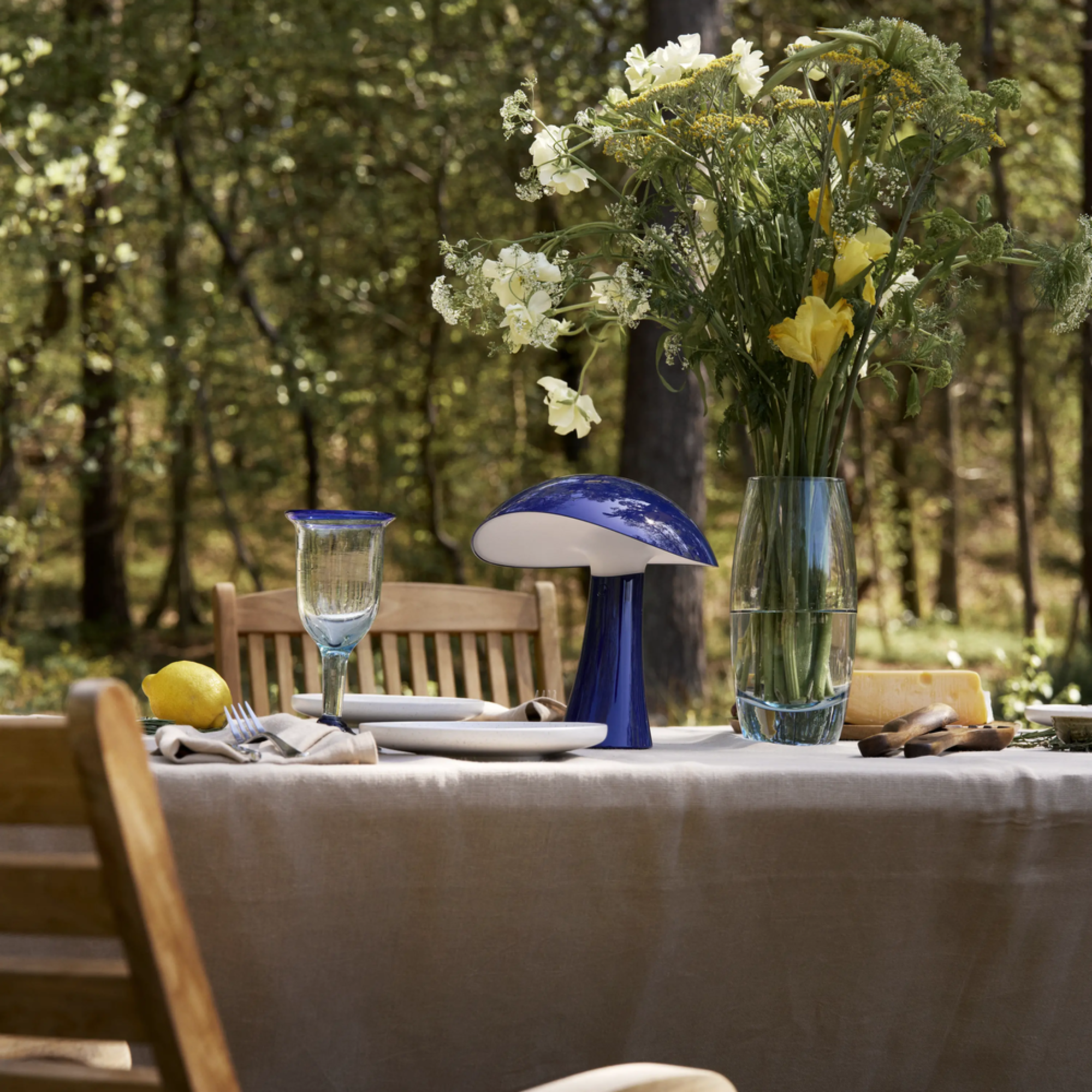 The night blue Rumee 220 Portable Lamp from Louis Poulsen in an outdoor dining space.