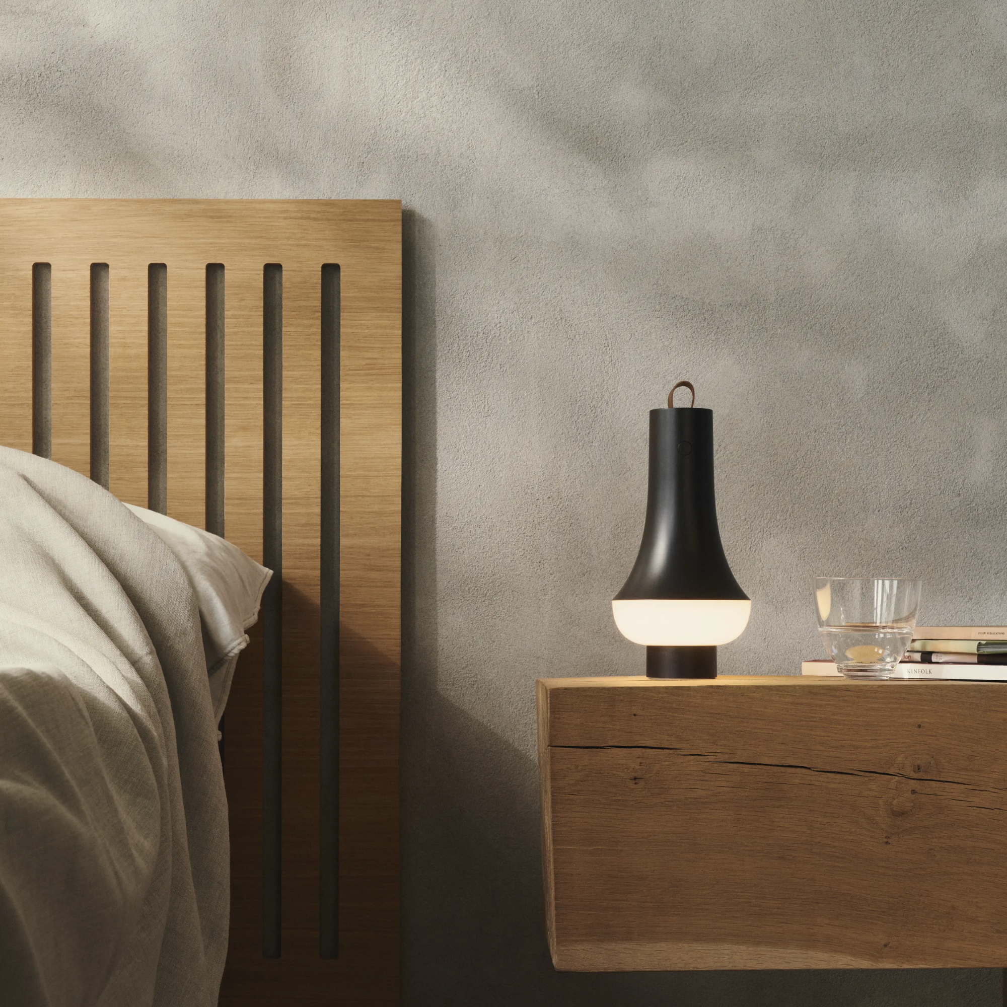 The dark brown Tomoshi Portable Lamp from Louis Poulsen in a luxury bedroom on a bedside table.