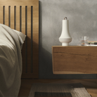 The white Tomoshi Portable Lamp from Louis Poulsen in a guest bedroom on top a wooden bedside table.