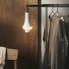 The white Tomoshi Portable Lamp from Louis Poulsen in a walk in closet on a clothing rack.
