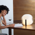 The Lito Classic Wood Cordless Book Lamp from Lumio in a dining room on top of a wood table. all-groups