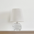 The Nicole Rechargeable LED Table Lamp from Mitzi in a bedroom on top of a wood surface.