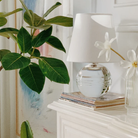 The Nicole Rechargeable LED Table Lamp from Mitzi in a guest bedroom on top of a couple magazines.
