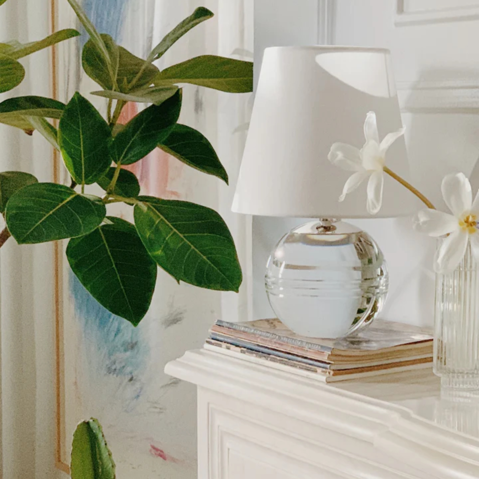 The Nicole Rechargeable LED Table Lamp from Mitzi in a guest bedroom on top of a couple magazines.