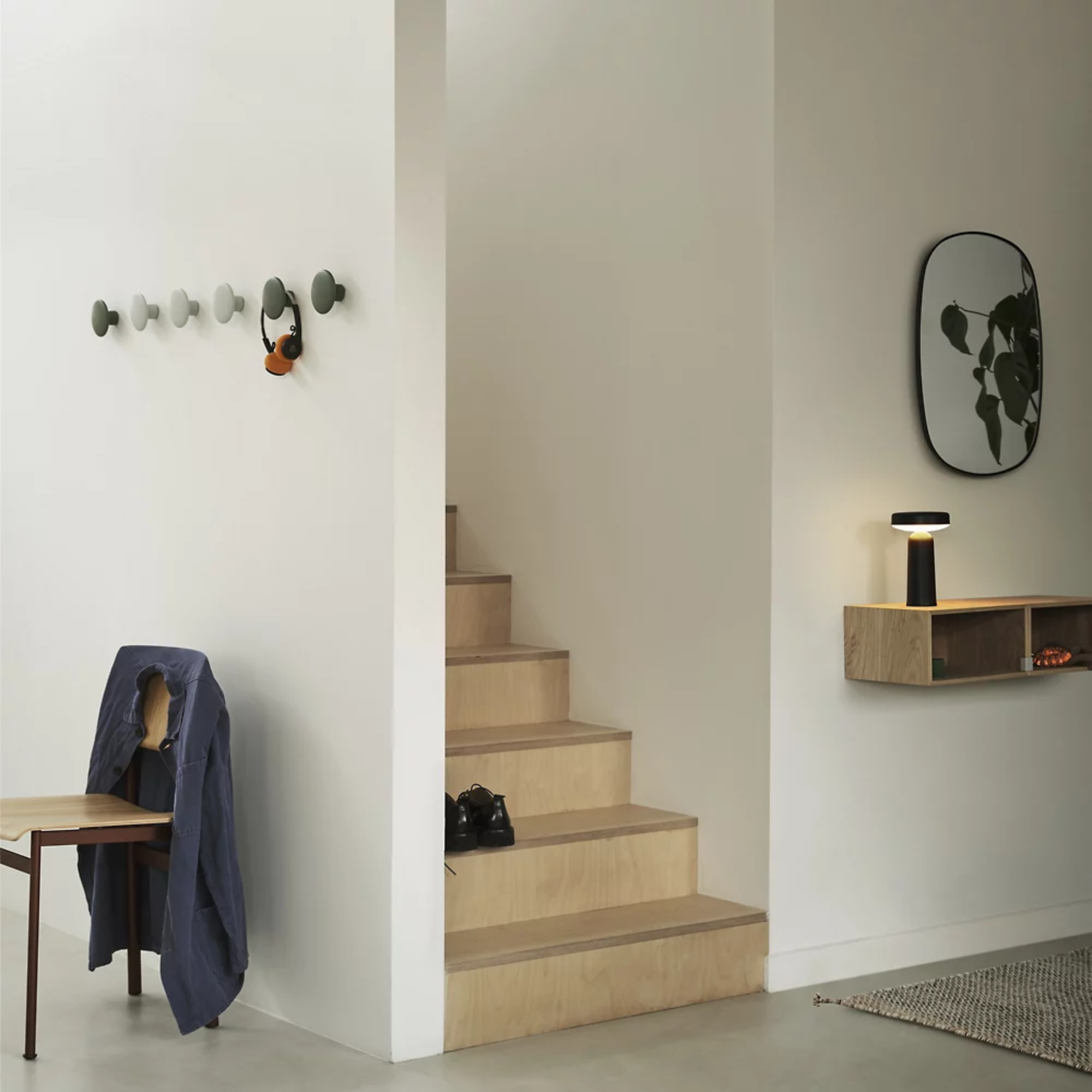 The black Ease Cordless Lamp from Muuto in a hallway on top of a floating shelf.