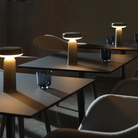 The gray Ease Cordless Lamp from Muuto in a cafe on top of three wooden tables.
