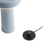 The light blue Ease Cordless Lamp from Muuto with its charging base. all-groups