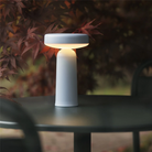 The light blue Ease Cordless Lamp from Muuto on top of a table at an outdoor cafe.