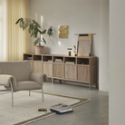 The taupe Ease Cordless Lamp from Muuto in a living room on top of a wooden console.
