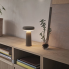 The taupe Ease Cordless Lamp from Muuto in a living space on top of a wooden table.