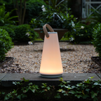 The Uma Sound Table Lamp from Pablo Designs in a garden.