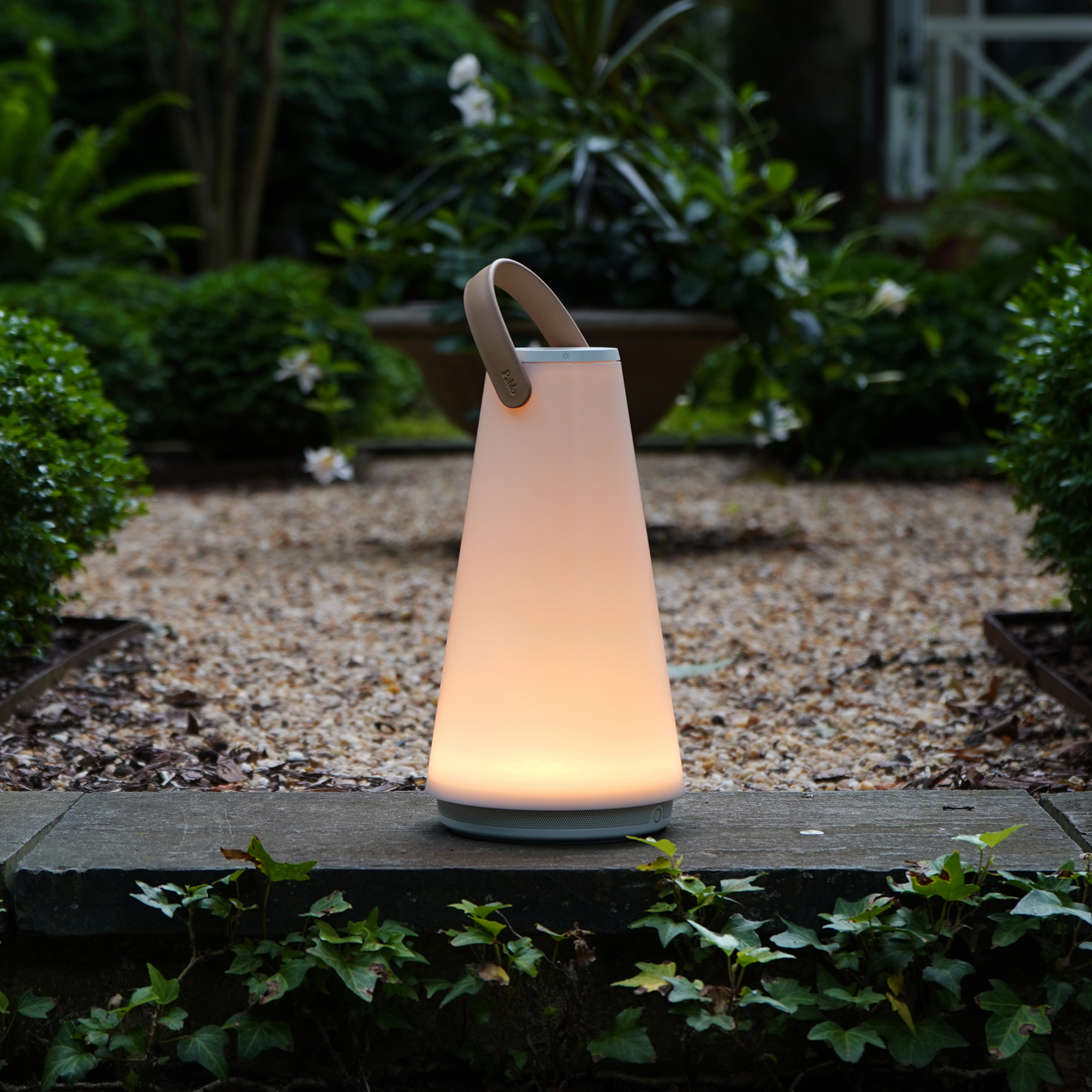 The Uma Sound Table Lamp from Pablo Designs in a garden.