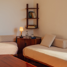 The Básica Mínima Batería Cordless Lamp from Santa & Cole with the stitched beige parchment shade in a lounge on an end table.