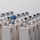 The baby blue Bell Cordless Lamp from Tom Dixon in a studio with multiple silver Bell lamps.