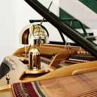 The gold Bell Cordless Lamp from Tom Dixon nestled on top of a piano in a lounge.