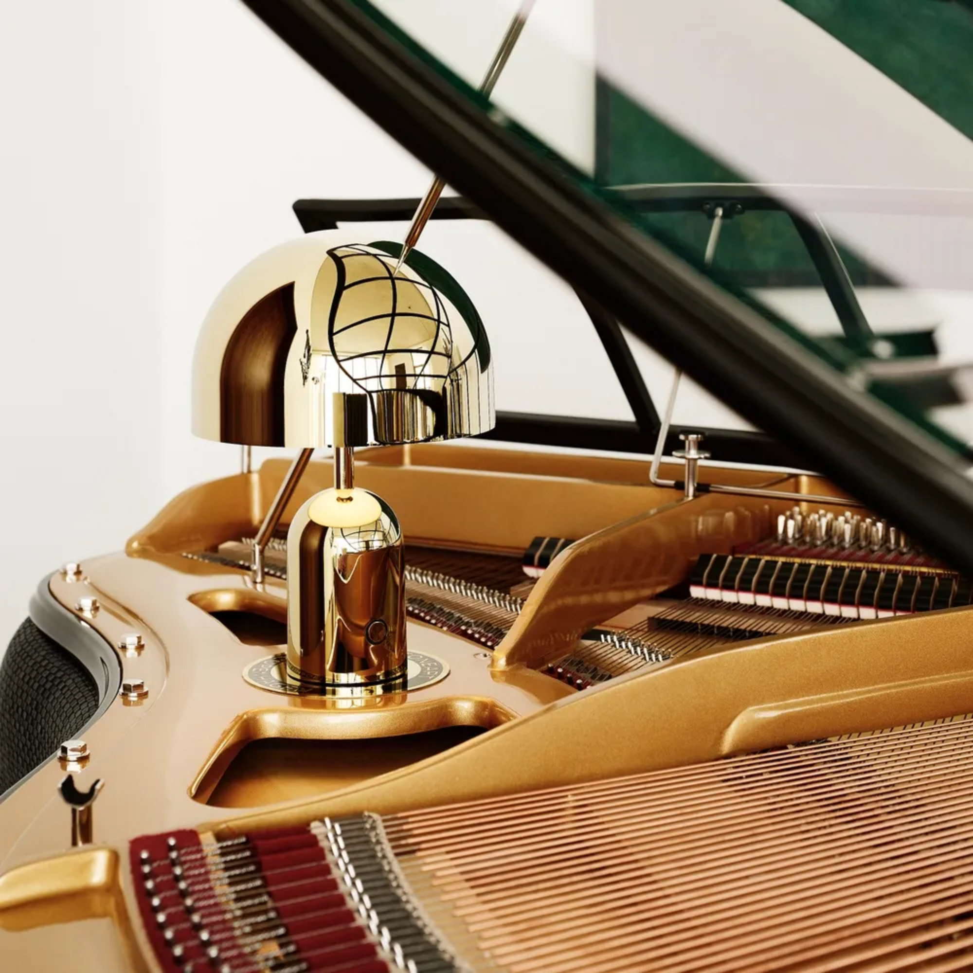 The gold Bell Cordless Lamp from Tom Dixon nestled on top of a piano in a lounge.