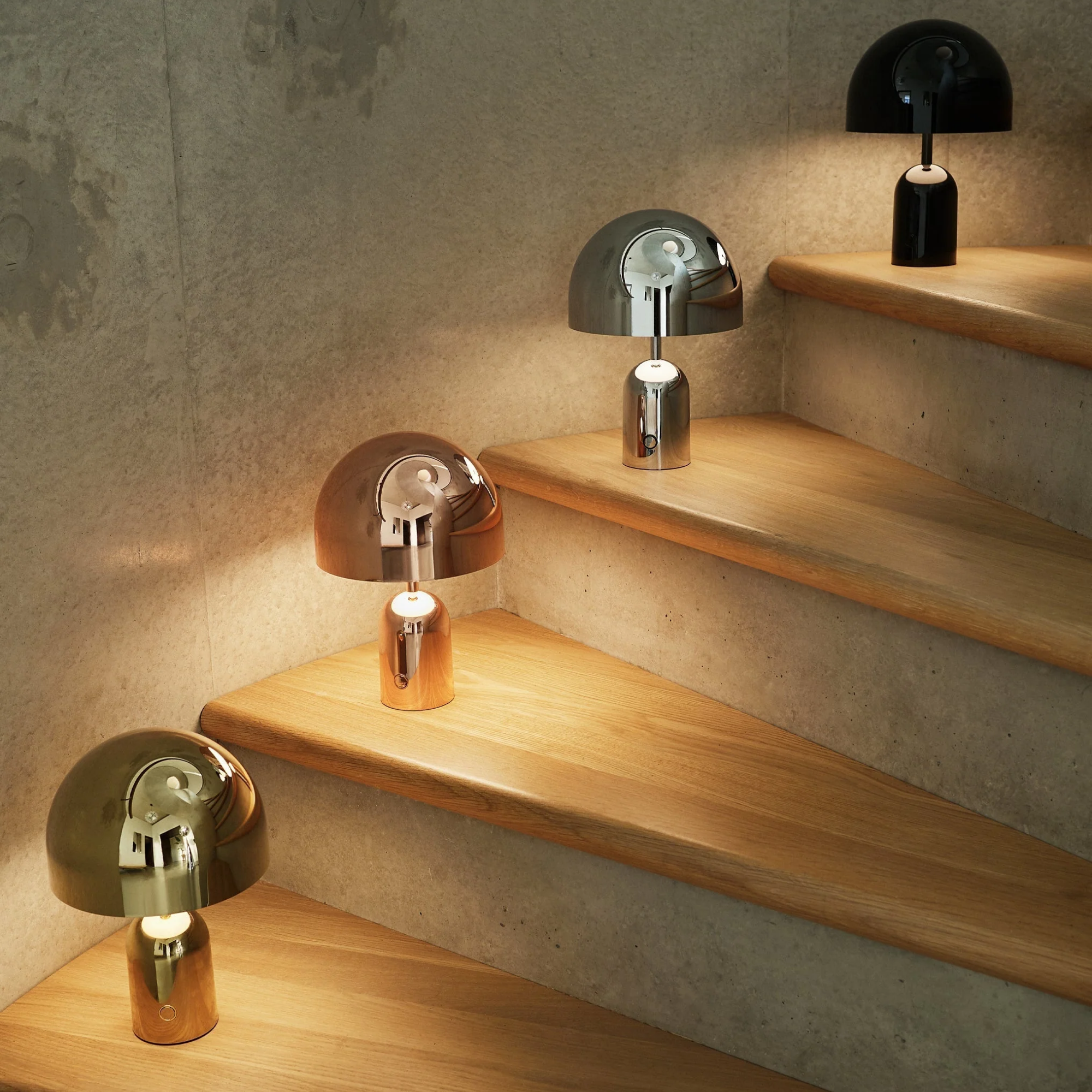 The gold Bell Cordless Lamp from Tom Dixon on a staircase with other Bell lights.