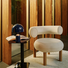 The indigo Bell Cordless Lamp from Tom Dixon shown in a lounge beside a lounge chair.