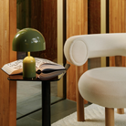 The moss Bell Cordless Lamp from Tom Dixon in a business office on top of a side table next to a chair.