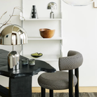 The silver Bell Cordless Lamp from Tom Dixon in a home office on the bookshelf with a vase, bowl, and other decor.