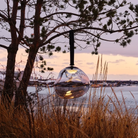 The smoke Melt Cordless Floor Lamp from Tom Dixon used at a coastal home, hung from a tree overlooking the water.