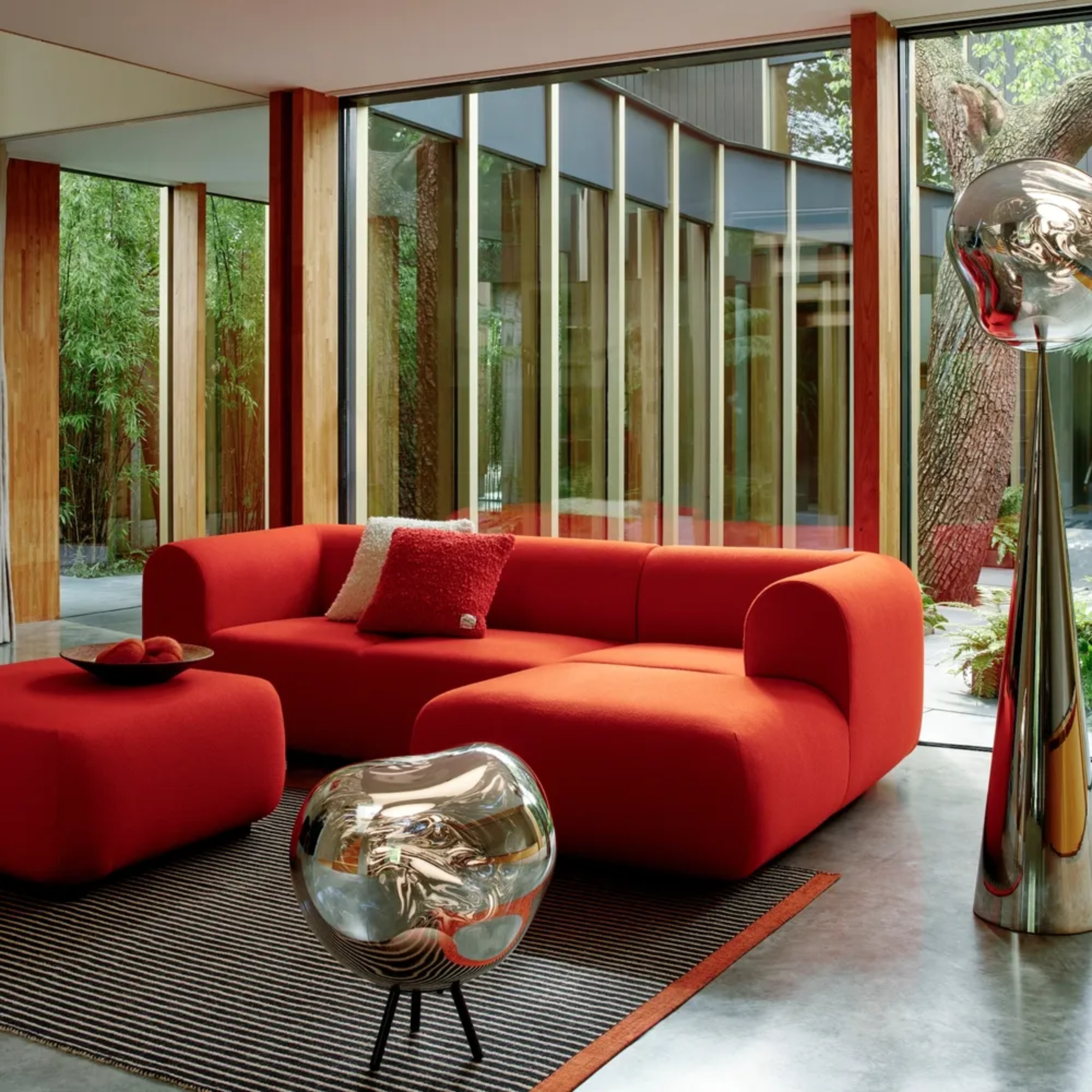 The smoke Melt Cordless Floor Lamp from Tom Dixon in a living room beside a sofa and ottoman.