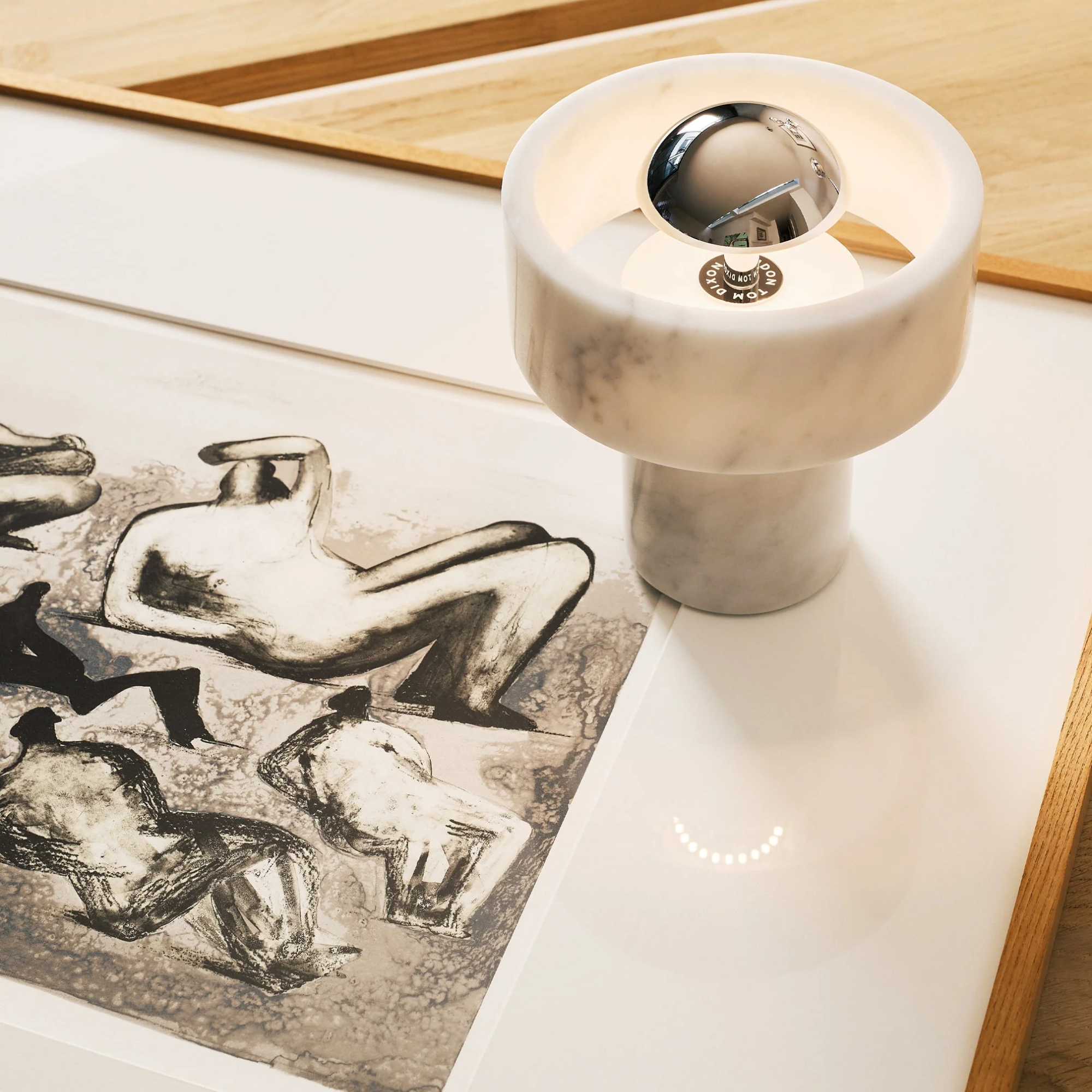 The silver Stone Cordless Lamp from Tom Dixon in an art gallery on top of an art piece.
