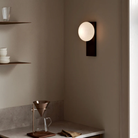 The black painted ash Dew Cordless Table Lamp & Wall Sconce from Woud in a kitchen and dining space.