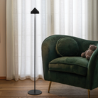 The black Amelie Pro Cordless Floor Lamp from Zafferano in a living room next to a lounge chair.