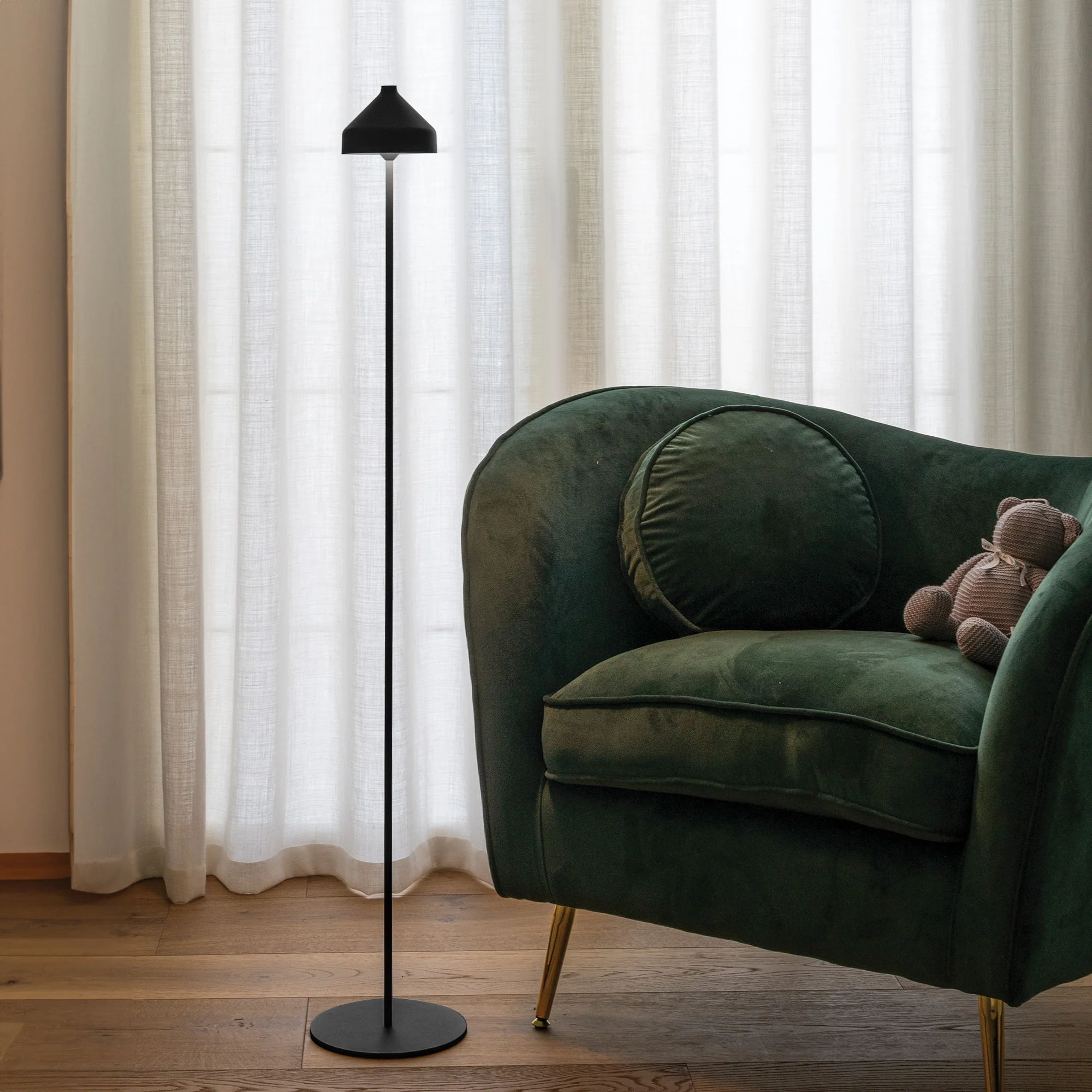The black Amelie Pro Cordless Floor Lamp from Zafferano in a living room next to a lounge chair.