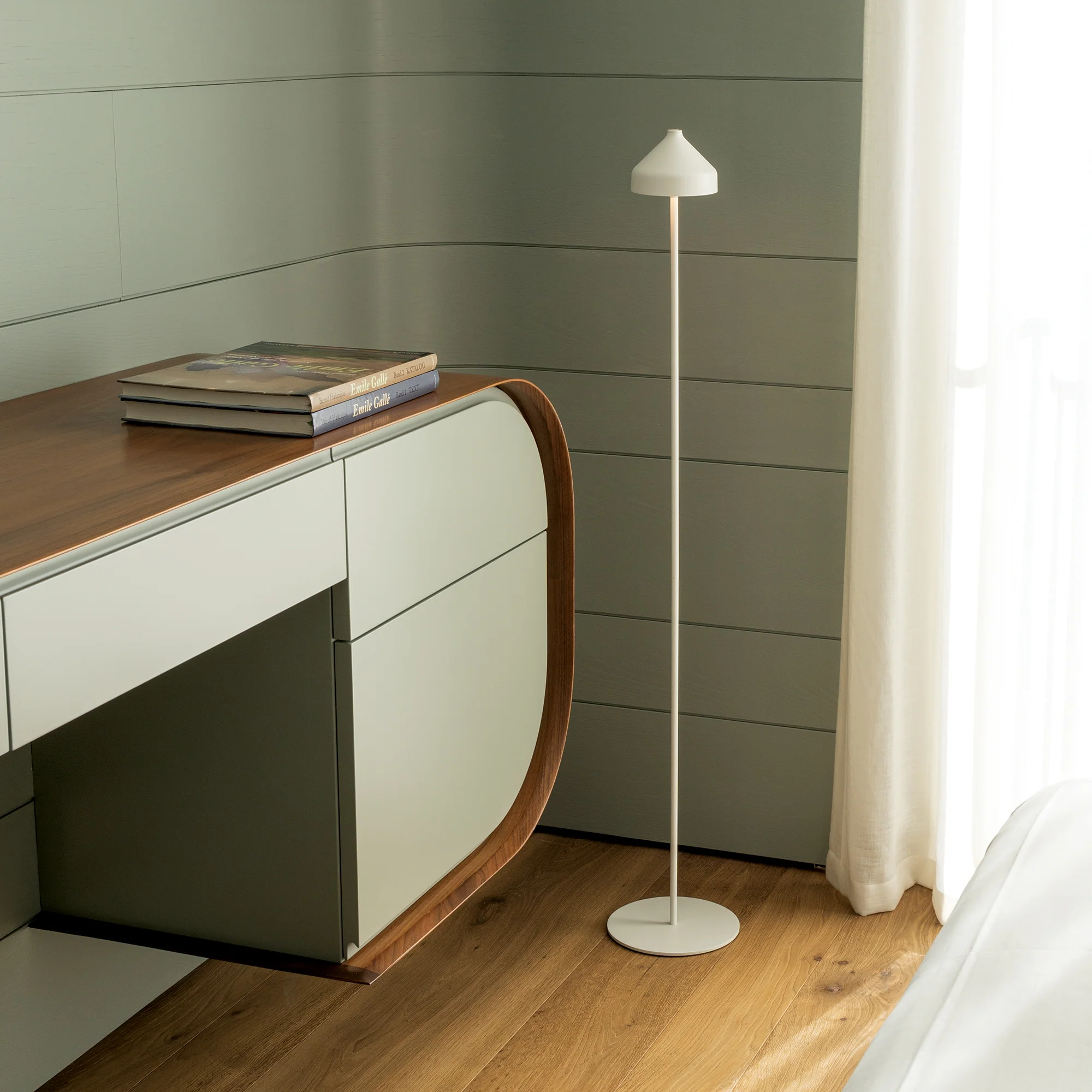 The white Amelie Pro Cordless Floor Lamp from Zafferano in a home office beside a desk.