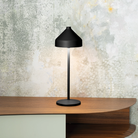 The black Amelie Pro Cordless Lamp from Zafferano in a home office on top of a table.