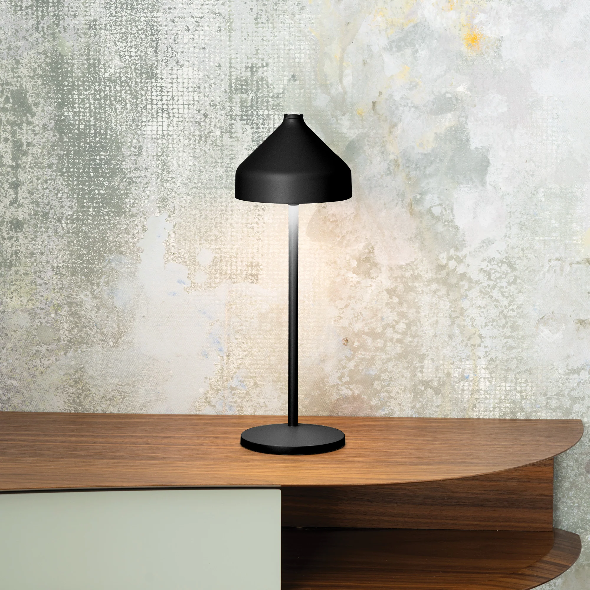 The black Amelie Pro Cordless Lamp from Zafferano in a home office on top of a table.